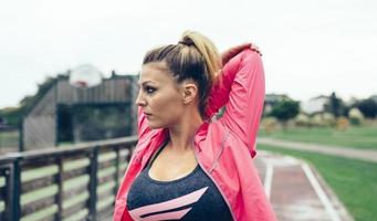 Young woman stretching arms before training outdoors photo