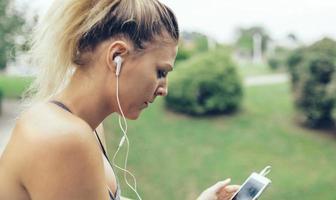 Woman with earphones listening music in smartphone photo