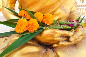Marigolds are placed on the Buddha statue as a sacrifice offering during the Buddhist Vesak Day feast. Flowers are associated with religious ideas or rituals. photo