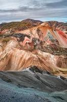 BeautifulIcelandic landscape of colorful rainbow volcanic Landmannalaugar mountains, at famous Laugavegur hiking trail with dramatic snowy sky, and red volcano soil in Iceland.