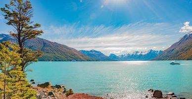 Panoramic view over glacial lagoon near gigantic Perito Moreno glacier in Patagonia with blue sky, turquoise water with icebergs and tour boats with tourists, South America, Argentina, at sunny day. photo