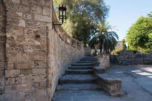 Beautiful ancient stairs at Rhodes town fortification. Palm tree and metal lamp. Rhodes, Dodecanese, Greece. photo