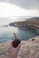 Man with small mate in hand on a Mediterranean beach. Mate is a typical drink from Paraguay, Argentina, Brazil and Uruguay. photo