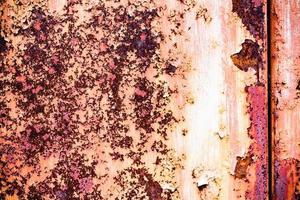 Brown grunge texture of an old metal wall covered in rust. Textured surface with an interesting pattern, dirty sheet metal with peeling paint. Weathered, rough and rust-eaten iron wall of the garage. photo