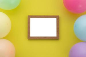 Happy birthday background, Flat lay colorful party decoration with photo frame on pastel yellow background