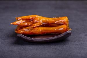 Stewed chicken feet are in the container in the dark background photo
