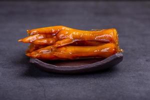 Stewed chicken feet are in the container in the dark background photo