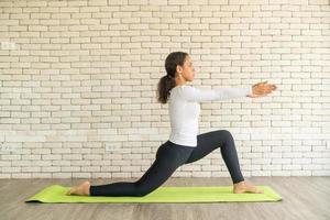 Latin woman practicing yoga on mat photo