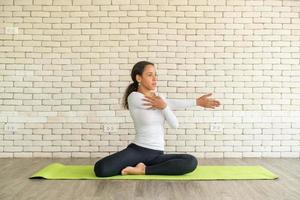 Latin woman practicing yoga on mat photo