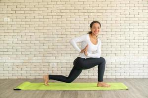 Latin woman practicing yoga on mat photo