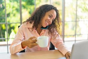 Mujer latina que trabaja con una taza de café en el espacio de trabajo