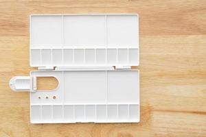 White watercolor palette. Empty watercolor tray isolated on wood background. photo