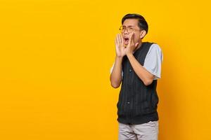 Retrato de un joven asiático gritando con expresión de asombro sobre fondo amarillo foto