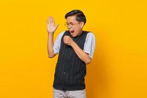 Happy young Asian man enjoying singing on yellow background photo