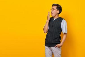 Portrait of handsome young Asian man feeling sleepy and covering mouth with hand photo