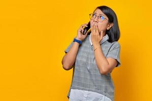 Sorprendido joven asiática al recibir una llamada entrante en el teléfono móvil y cubrirse la boca con la mano foto
