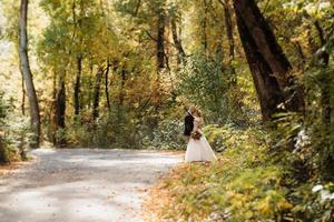 paseo de la novia y el novio por el bosque de otoño foto