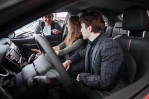 Proud owners. Beautiful young happy couple hugging standing near their newly bought car smiling joyfully showing car keys to the camera copyspace family love relationship lifestyle buying consumerism photo