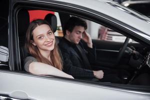 Proud owners. Beautiful young happy couple hugging standing near their newly bought car smiling joyfully showing car keys to the camera copyspace family love relationship lifestyle buying consumerism photo