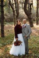 walk of the bride and groom through the autumn forest photo