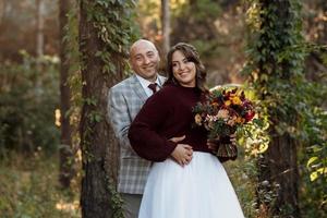 walk of the bride and groom through the autumn forest photo