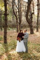 walk of the bride and groom through the autumn forest photo