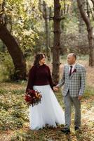 walk of the bride and groom through the autumn forest photo