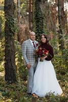 walk of the bride and groom through the autumn forest photo