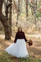 niña en un vestido de novia en el bosque de otoño foto