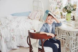 Photo of diligent schoolboy with book on his head does not want to study and go to school