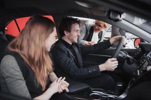 Making their decision. Beautiful loving couple sitting in a new car together at the dealership handsome man and his loving girlfriend choosing a car together consumerism vehicle photo