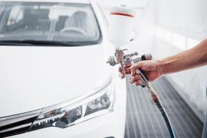 pistola con pintura en las manos de un hombre para pintar un coche foto