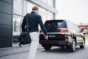 A young, solid businessman and his car near the office photo