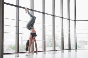 A sports sports woman who is doing yoga classes, stretching her legs near the big window photo