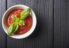 overhead view tomato sauce with green basil leaves wooden backdrop. photo