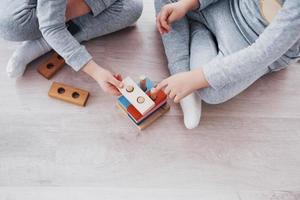 Children play with a toy designer on the floor of the children's room. Two kids playing with colorful blocks. Kindergarten educational games photo