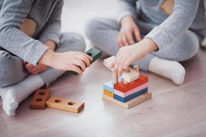 Children play with a toy designer on the floor of the children's room. Two kids playing with colorful blocks. Kindergarten educational games photo