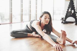 Stretching a gymnast woman makes a split, a twine in a gym. photo