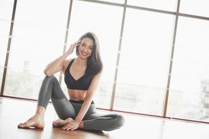 Stretching a gymnast woman makes a split, a twine in a gym. photo