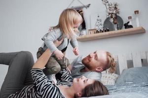 Happy family together. Mother, father and child daughter hugging in bedroom in festive day photo