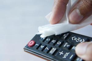 Cleaning Tv remote control with an antibacterial fabric tissue.. photo