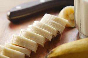 close up of slice of banana glass of milk on table photo