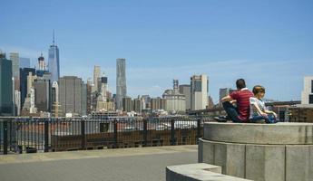 Man and boy sitting in front of Manhattan skyline, in New York City photo