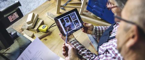 Senior couple in a carpentry looking tablet photo