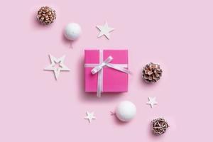 regalo de navidad y adornos. composición navideña simple en superficie rosa pastel. vista superior, plano