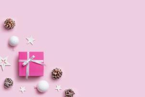 regalo de Navidad y adornos en el escritorio de color rosa pastel con espacio de copia al lado del texto de saludo. vista superior, composición plana foto