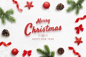 feliz navidad y próspero año nuevo tarjeta de felicitación con desviaciones navideñas. texto rojo rodeado de ramas de árboles, bolas, estrellas, conos, arcos. foto