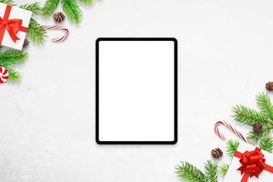 Tablet mockup on white desk with Christmas decorations. Top view, flat lay composition photo