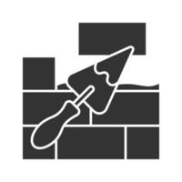 Brick wall with triangular shovel glyph icon. Putty knife, spatula. Cement solution. Silhouette symbol. Negative space. Vector isolated illustration