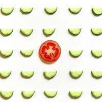 repeating pattern of sliced semicircles of fresh raw vegetable cucumbers for salad and tomato photo